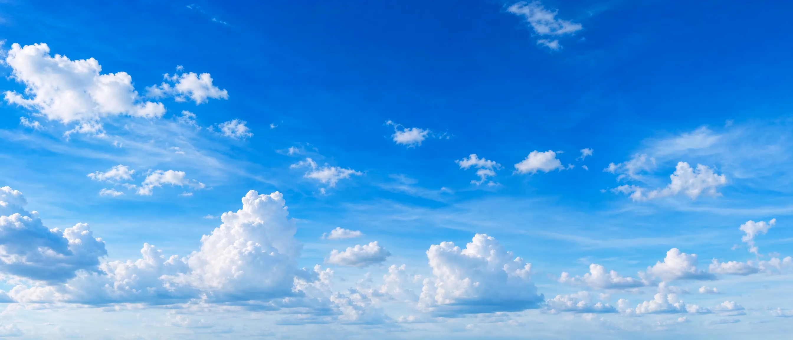 Bright blue sky filled with scattered fluffy white clouds.